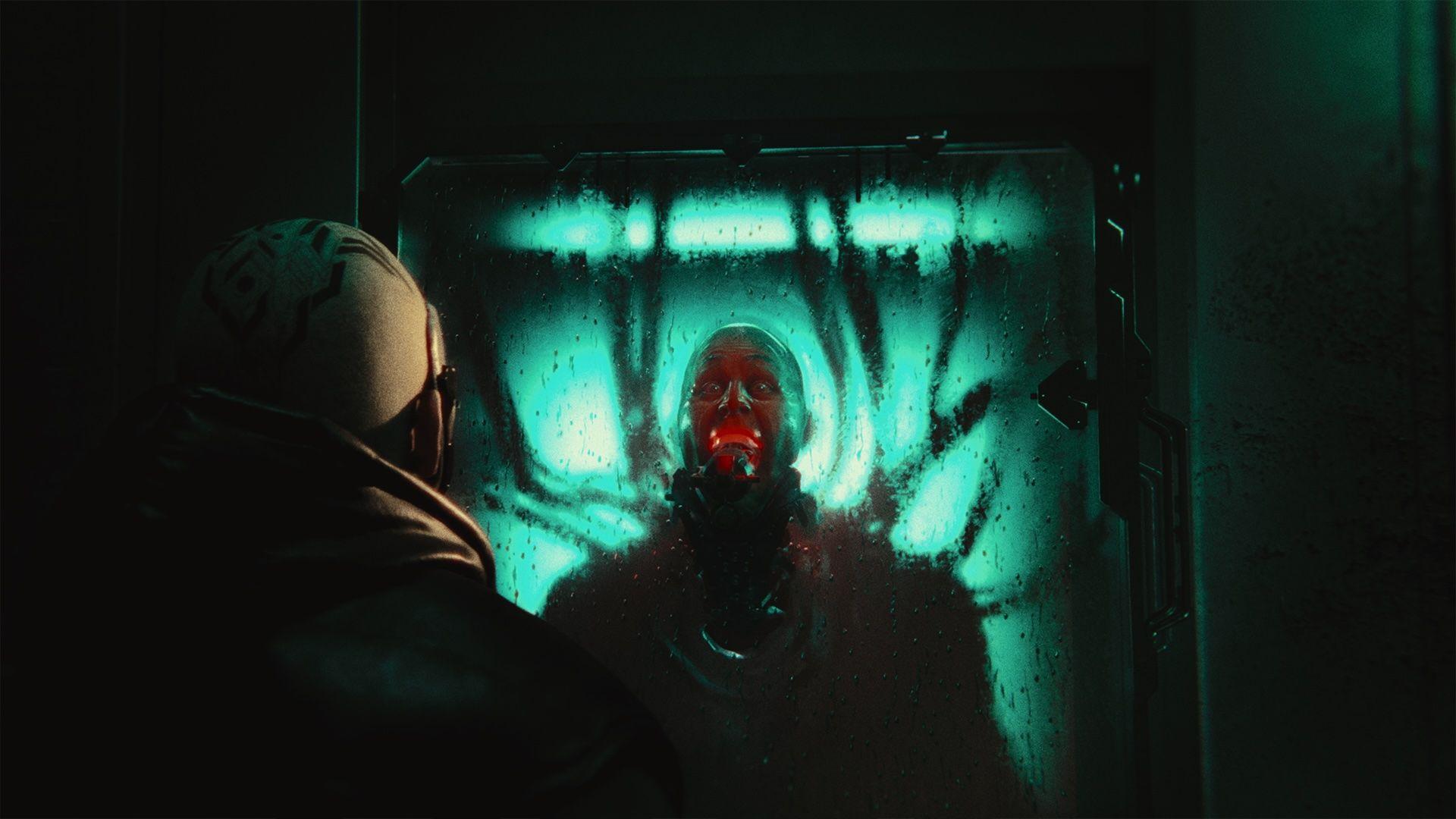 a person looking into a window of another person looking maniacal with chords behind him